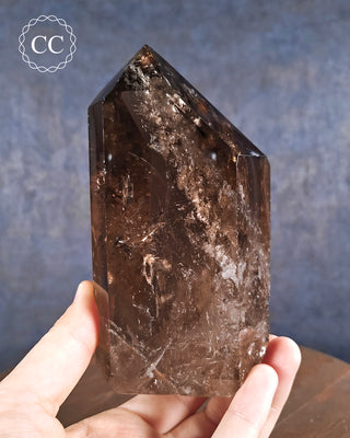 Smoky Quartz Tower in hand on blue background