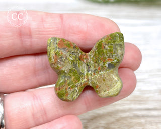 A hand holding one Unakite butterfly carving