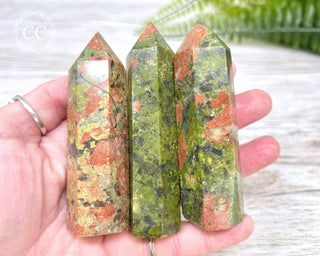 A hand holding three Unakite crystal towers