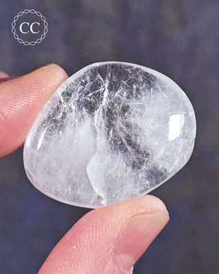A hand holding a polished White Apophyllite crystal