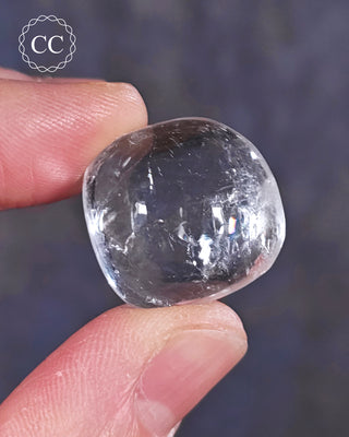 A hand holding a polished White Apophyllite crystal