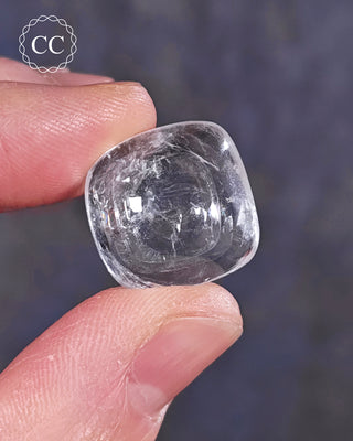 A hand holding a polished White Apophyllite crystal