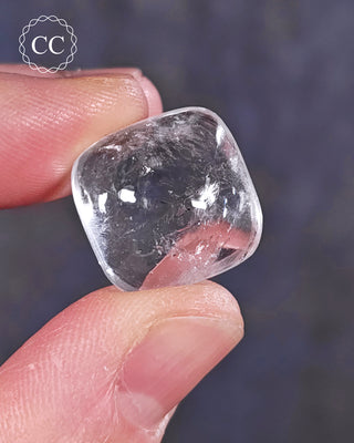 A hand holding a polished White Apophyllite crystal