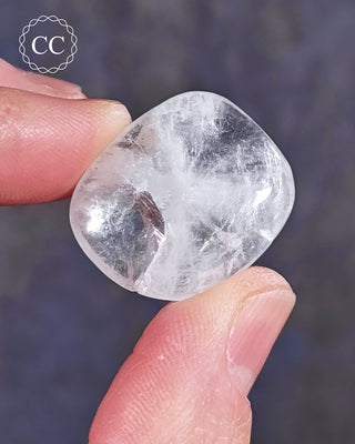 A hand holding a polished White Apophyllite crystal