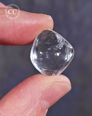 A hand holding a polished White Apophyllite crystal