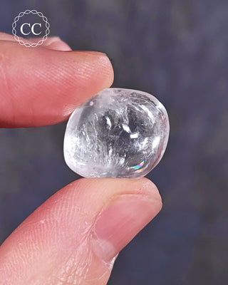 A hand holding a polished White Apophyllite crystal