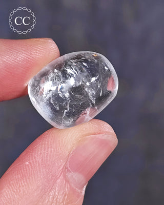 A hand holding a polished White Apophyllite crystal