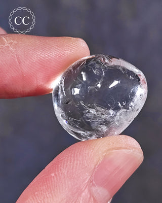 A hand holding a polished White Apophyllite crystal