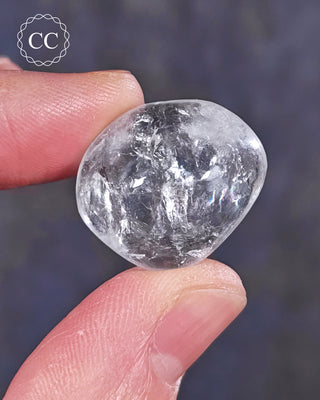 A hand holding a polished White Apophyllite crystal