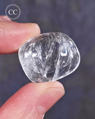 A hand holding a polished White Apophyllite crystal