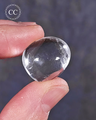 A hand holding a polished White Apophyllite crystal