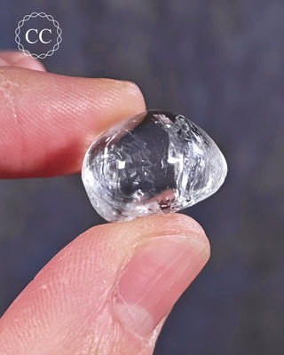 A hand holding a polished White Apophyllite crystal