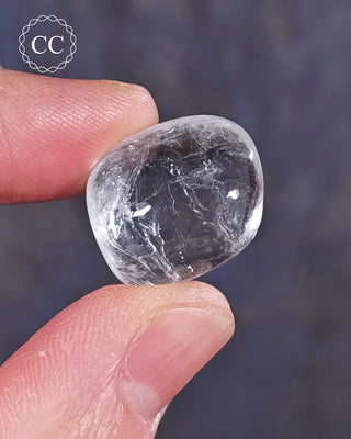 A hand holding a polished White Apophyllite crystal