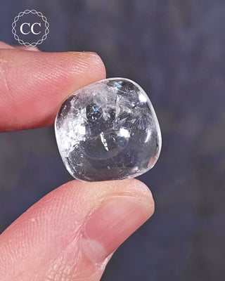 A hand holding a polished White Apophyllite crystal