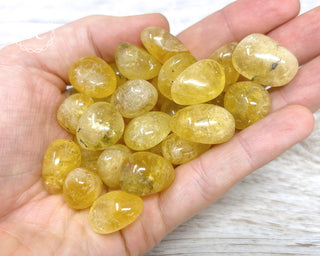 A hand holding a selection of Yellow Blue John Tumbled Crystals